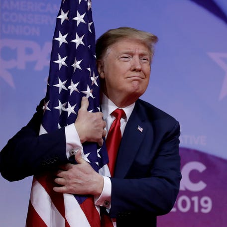 President Donald Trump hugs American flag at the Conservative Political Action Conference annual meeting at National Harbor near Washington, on March 2, 2019.