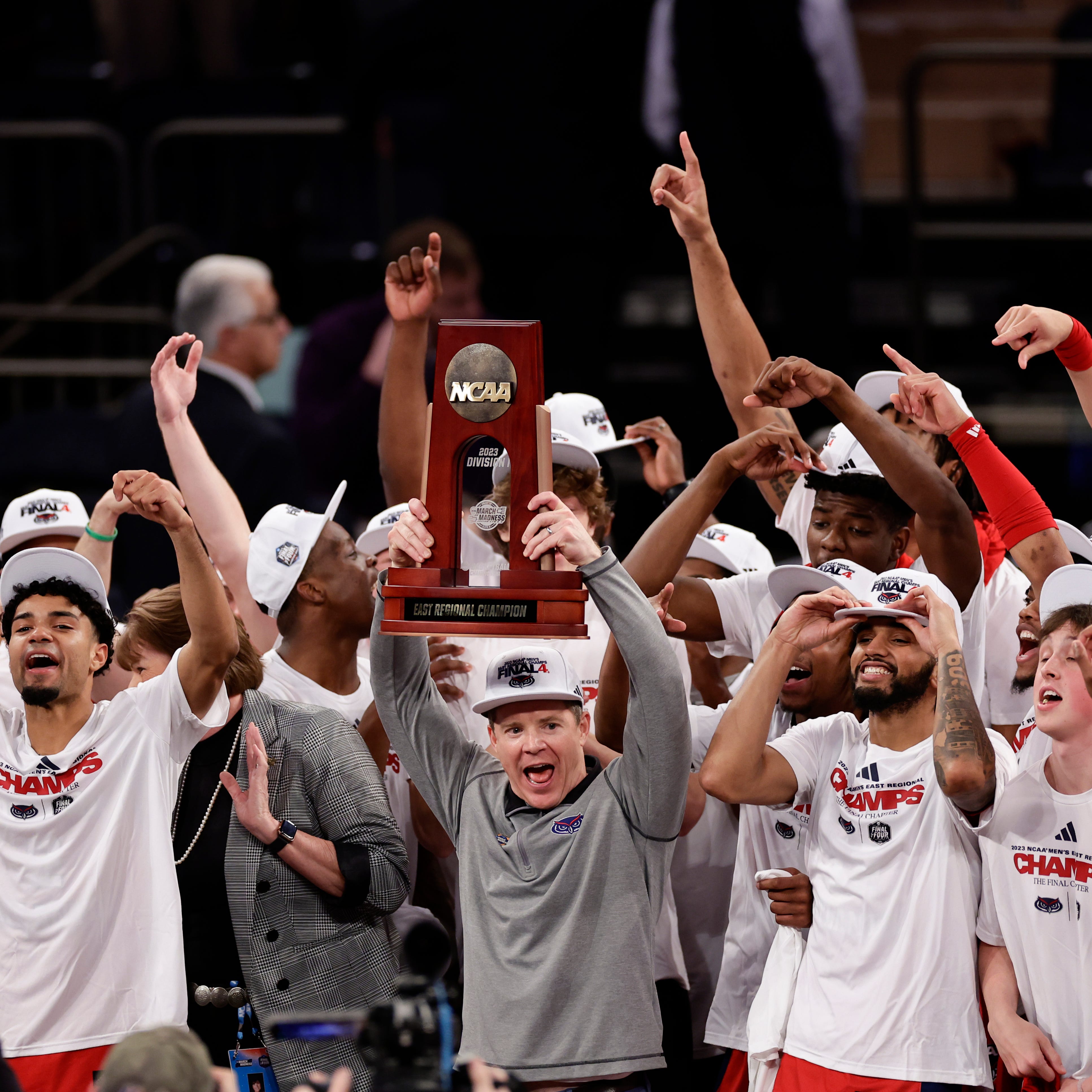 Florida Atlantic head coach Dusty May holds up the trophy as Florida Atlantic players celebrate after defeating Kansas State in the second half of an Elite 8 college basketball game in the NCAA Tournament's East Region final, Saturday, March 25, 2023, in New York. (AP Photo/Adam Hunger)