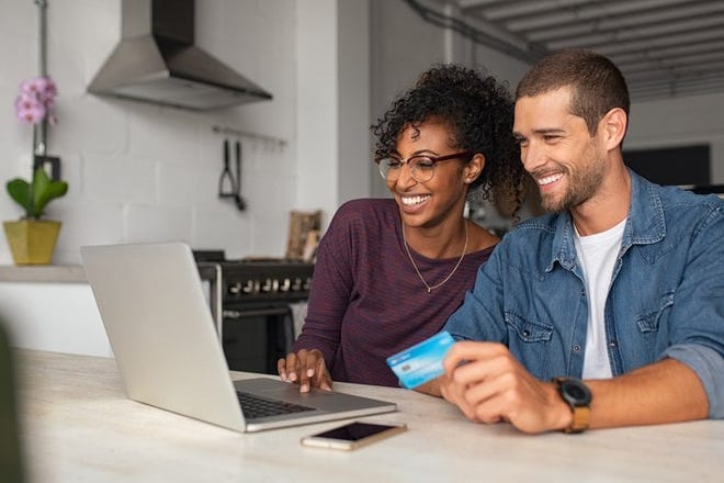 A man and woman shopping online with a credit card