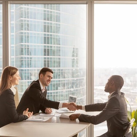 An employee shaking hands with his two bosses acro