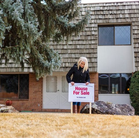 A person putting a House for Sale sign in the fron