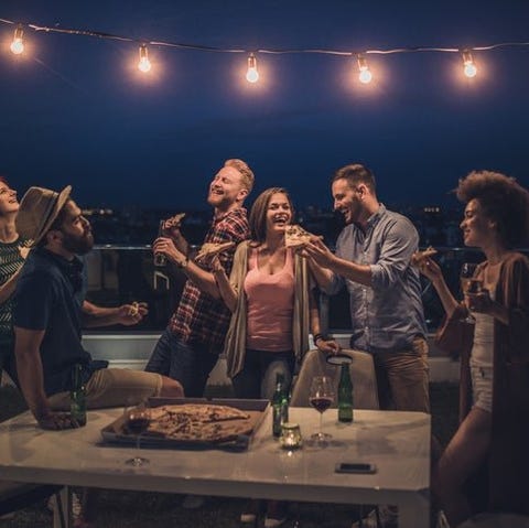 A group of laughing friends sharing pizza and beer