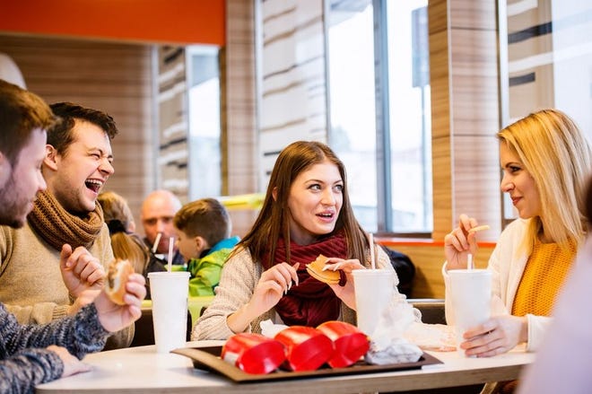 Group of friends eating fast food burgers and fries