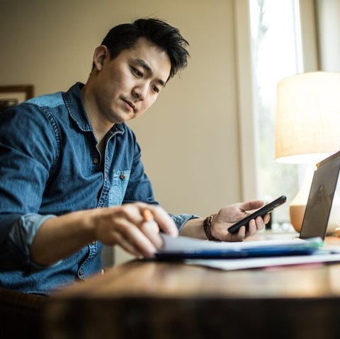 A person flips through papers at a home desk with 