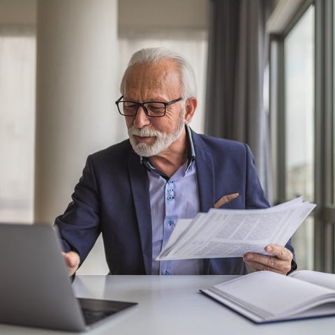 A person at a laptop holding papers.