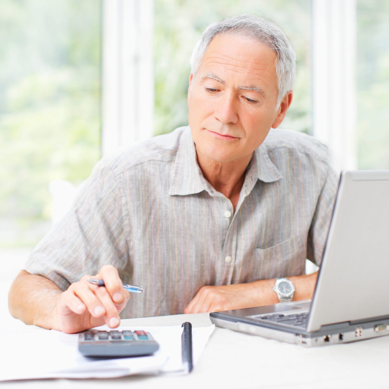 A person sitting at a table with a laptop and calculator.
