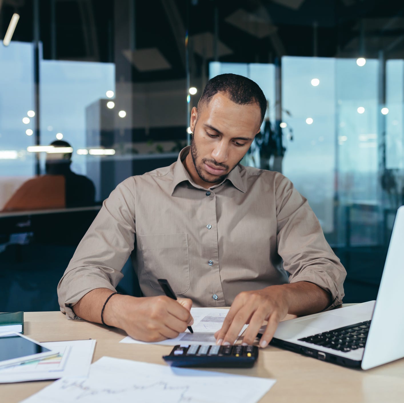 A person at a desk with a laptop and calculator.
