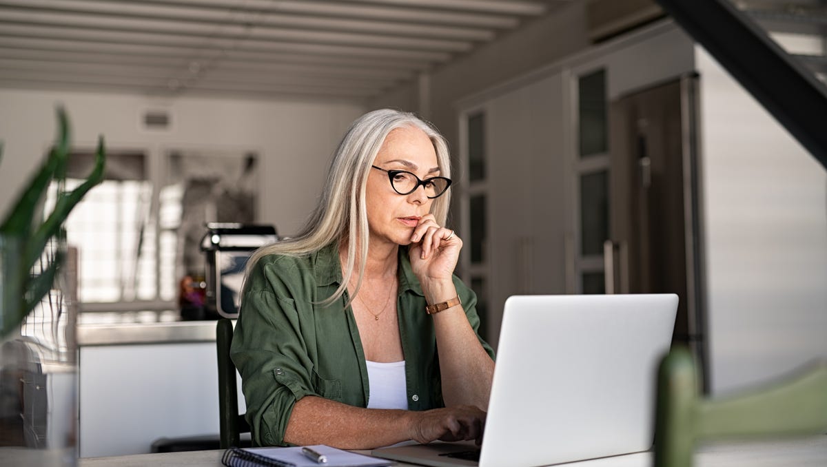 Serious person with hand on chin looking at laptop.
