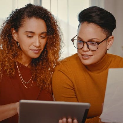 Two people at home looking at a tablet and paperwork.