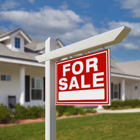 A house with a "for sale" sign in front of it.
