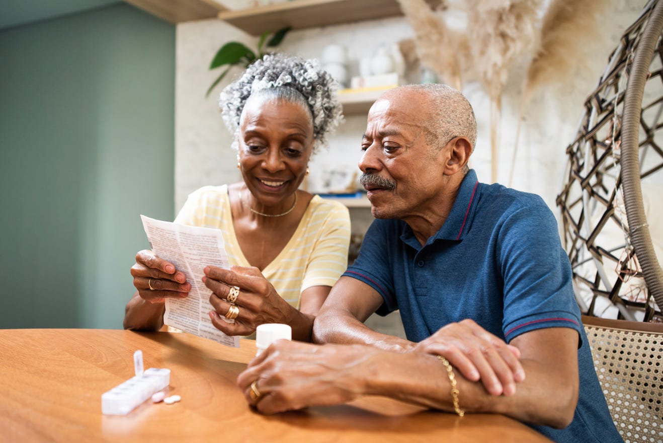 Couple sitting at table looking at document.