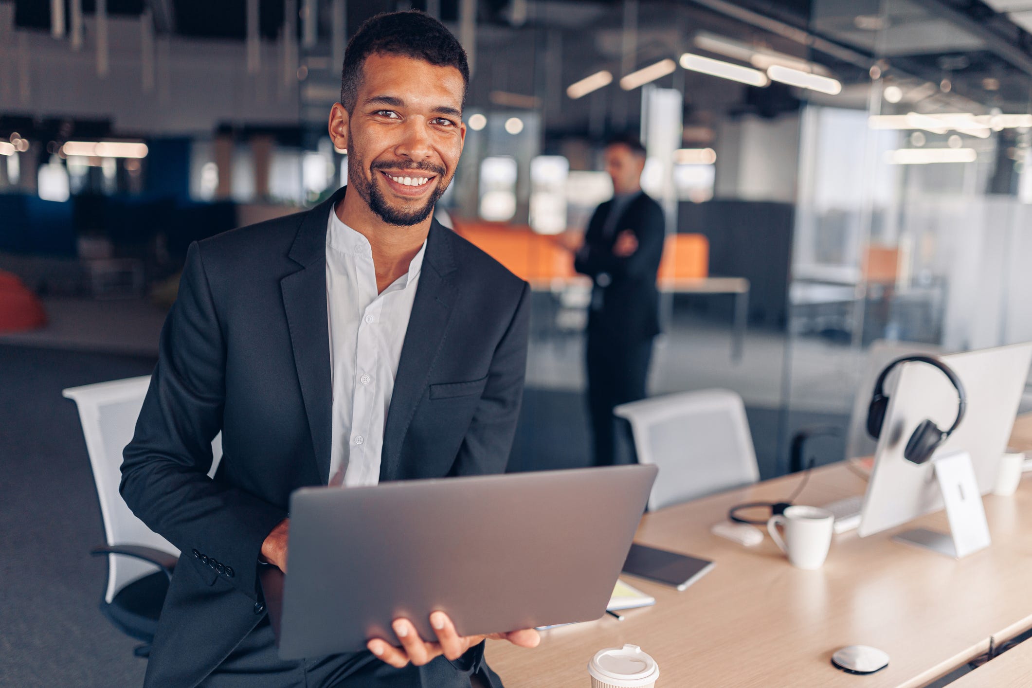 A smiling person holding a laptop.