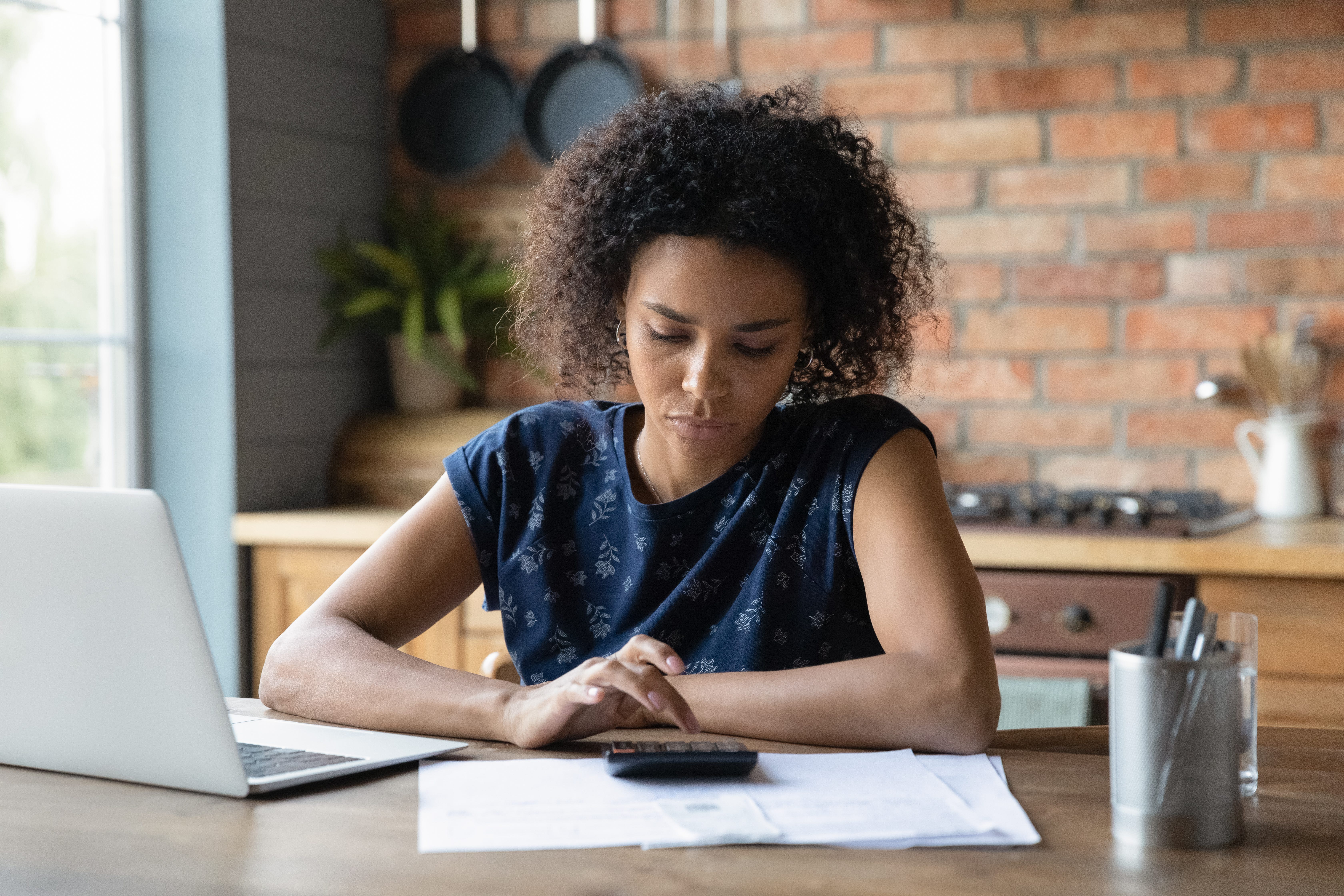 Person looking at paperwork and using calculator.