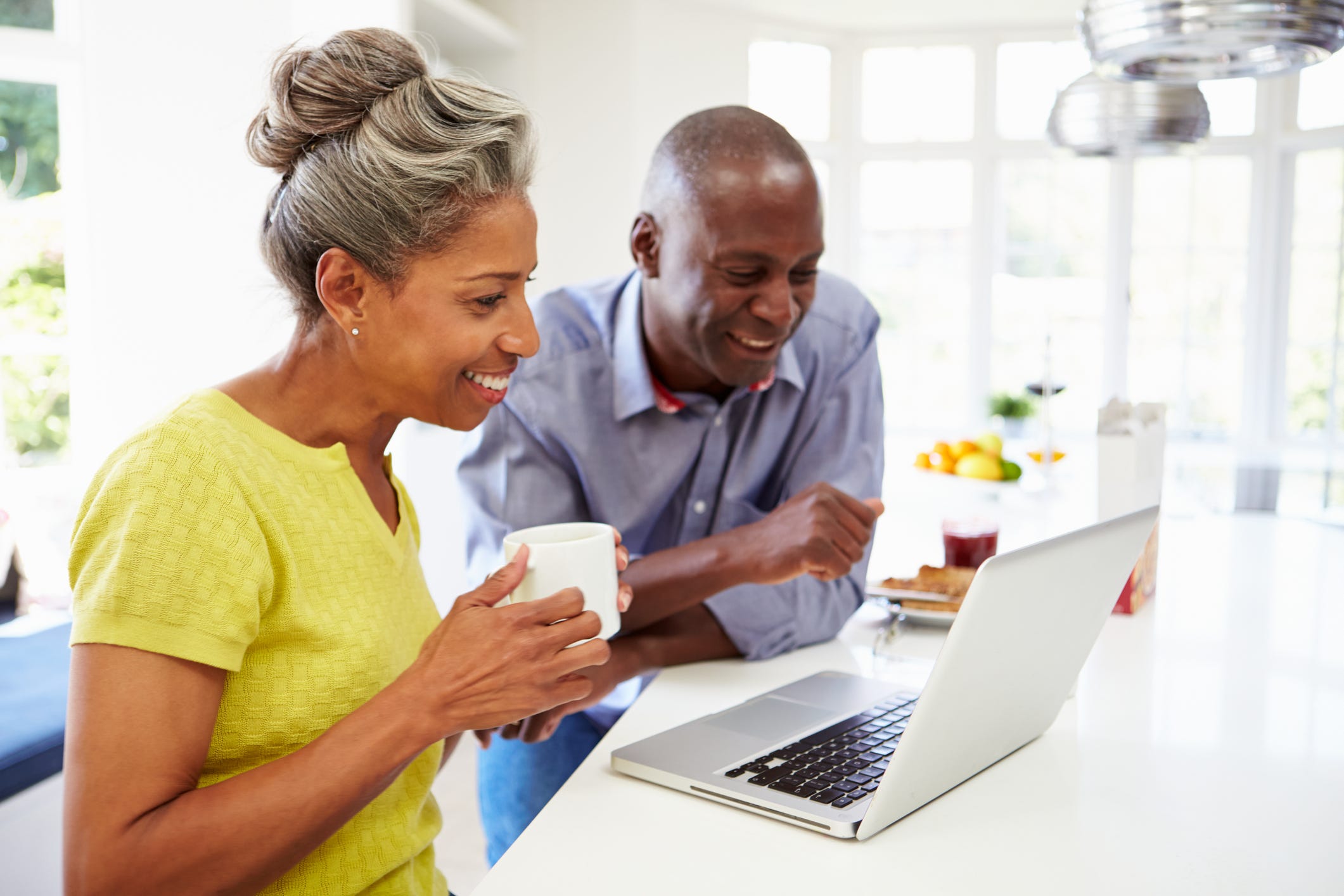 Two smiling people looking at a laptop.