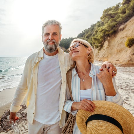 Older couple walking on a beach.