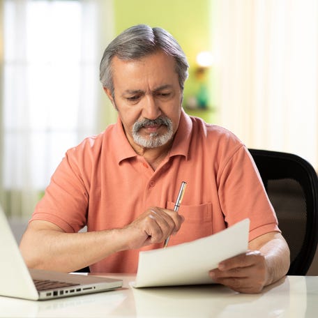Person holding pen and looking at document.