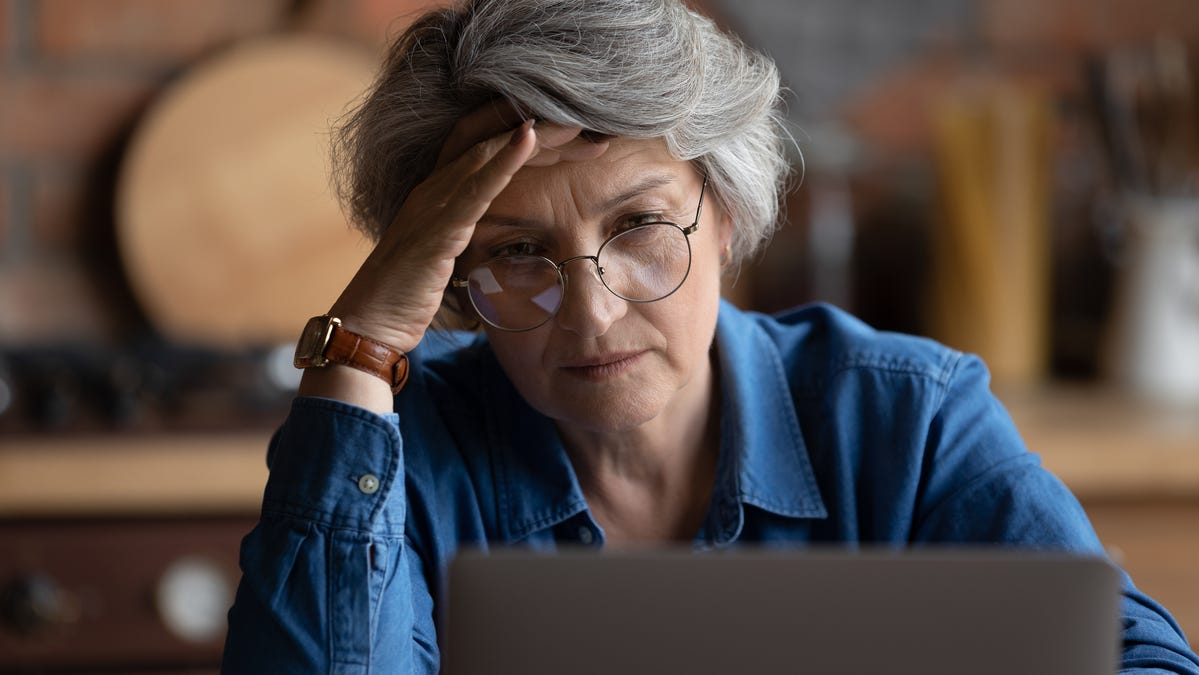 Frustrated person with hand on head looking at laptop.
