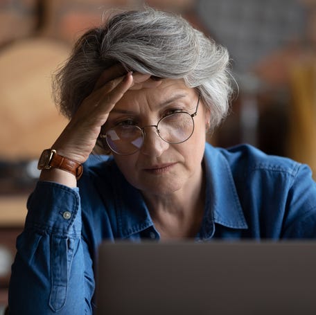 Frustrated person with hand on head looking at laptop.