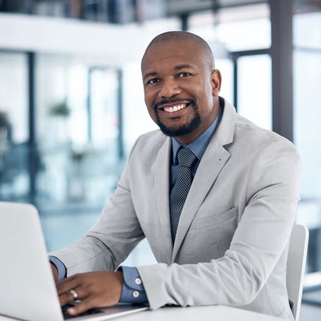 A smiling person at a laptop.