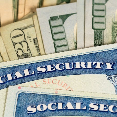 Two Social Security cards lay atop U.S. currency.