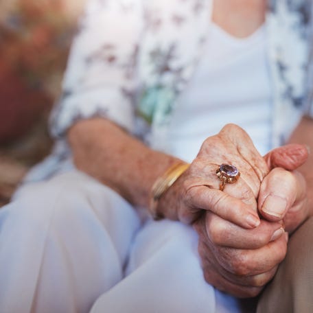 An elderly couple holding hands.