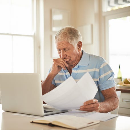 A person at a laptop holding documents.