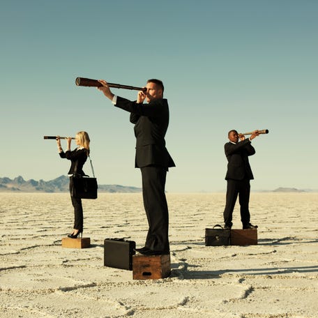 Business people looking through telescopes.