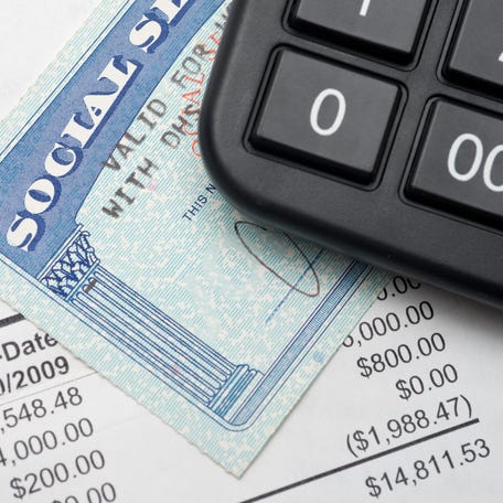 A calculator sitting on the corner of a Social Security card on top of a financial statement.