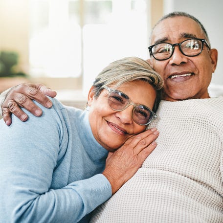 Two people hugging while sitting on a couch.