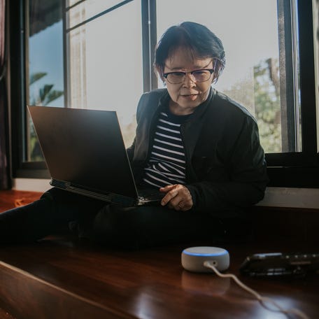 Person talking on the phone while typing on a laptop.