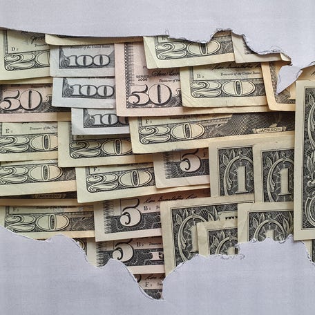 Assorted cash bills laid out and overlapping within the outline of the United States map.