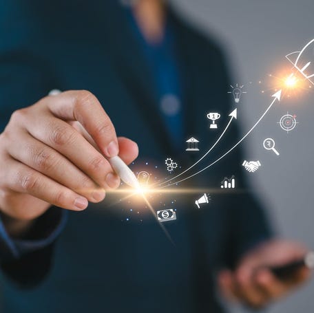 A hand drawing a picture of a rocket ship taking off.