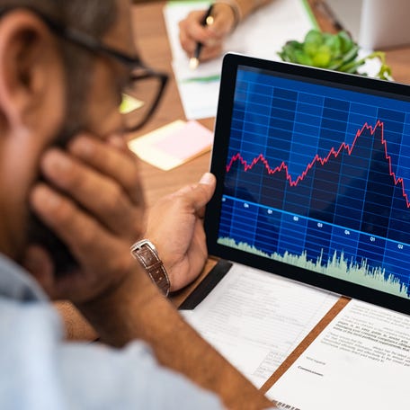 A visibly worried investor looking at a rapidly rising then plunging stock chart on a tablet.