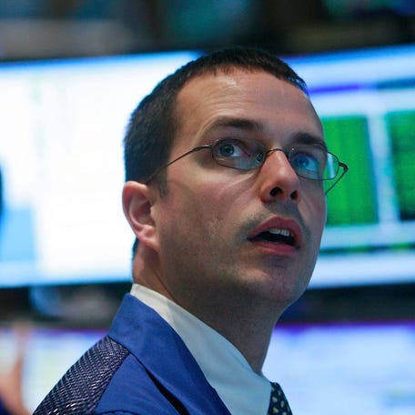 A New York Stock Exchange floor trader looking up in awe at a computer monitor.