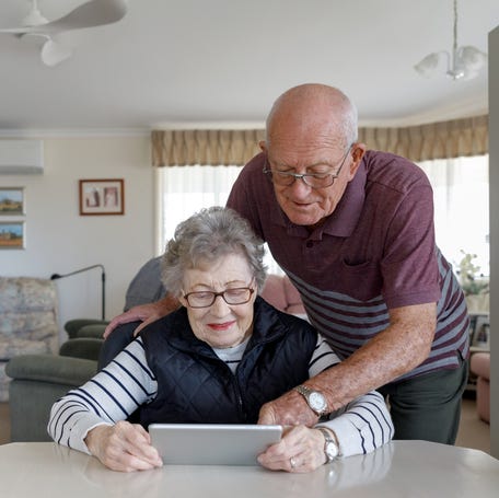 Smiling couple looking at tablet together.