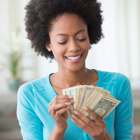 Person holding a stack of dollar bills.