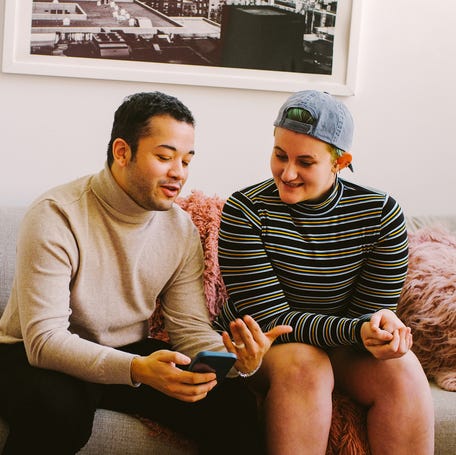 Two people smiling and looking at a smartphone.