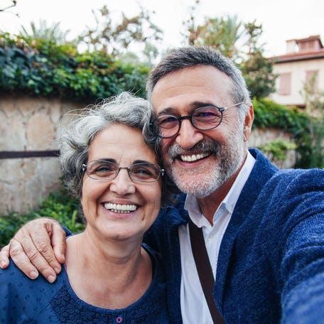 A couple is outdoors, smiling together for a selfie.
