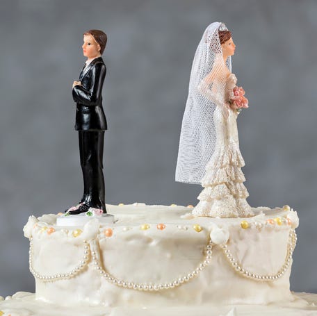 Bride and groom cake toppers staring in opposite directions.