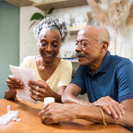 Two people sitting at a kitchen table, looking over paperwork.