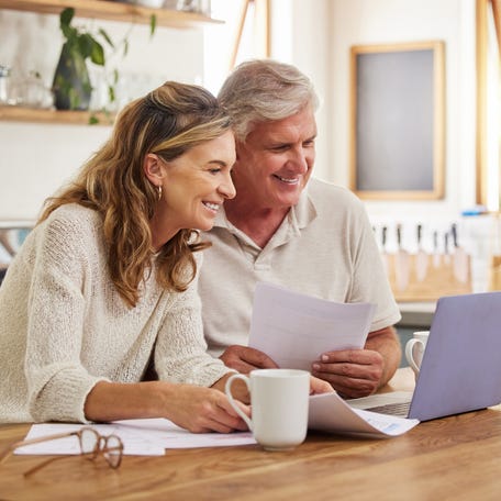 Two smiling people at a laptop.