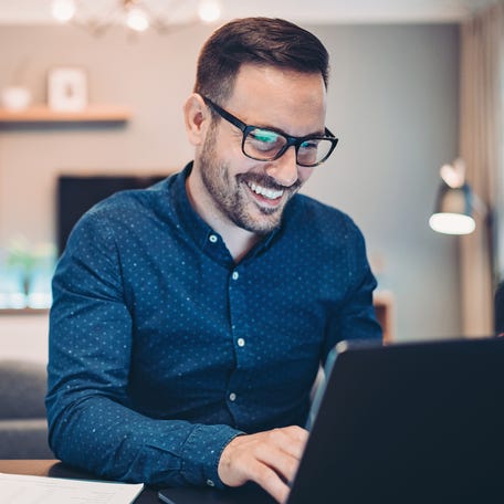 A smiling person at a laptop.