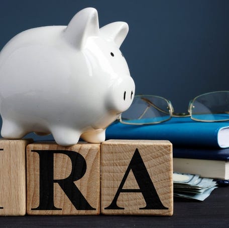 A piggy bank sitting on top of three blocks labeled "I, R, and A."