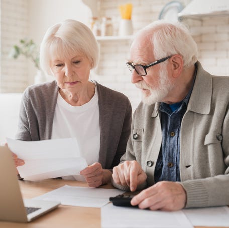 Two people at a laptop looking at a document.