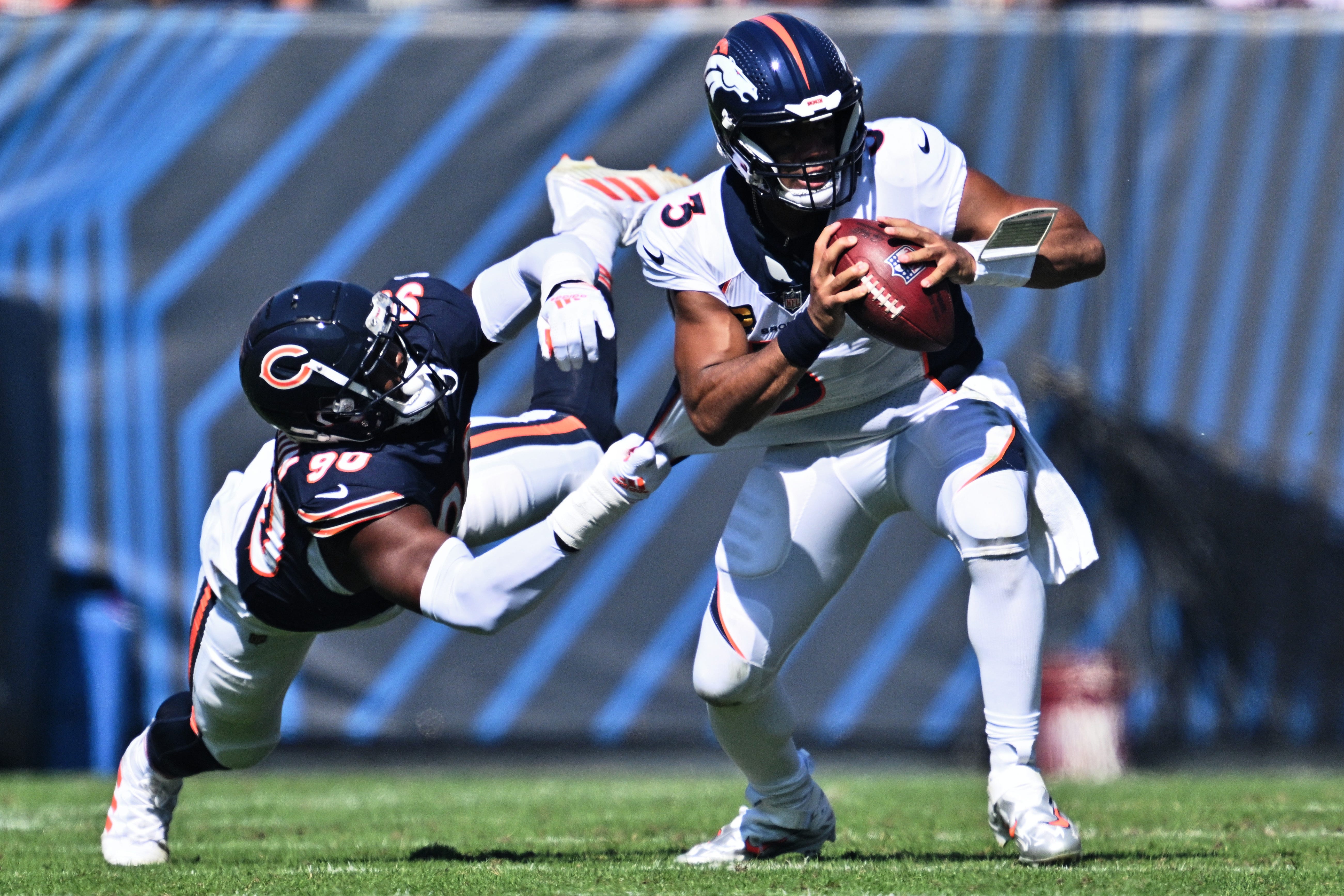 Oct 1, 2023; Chicago, Illinois, USA; Chicago Bears defensive lineman Dominique Robinson (90) holds on to Denver Broncos quarterback Russell Wilson (3) for a sack in the second quarter at Soldier Field.