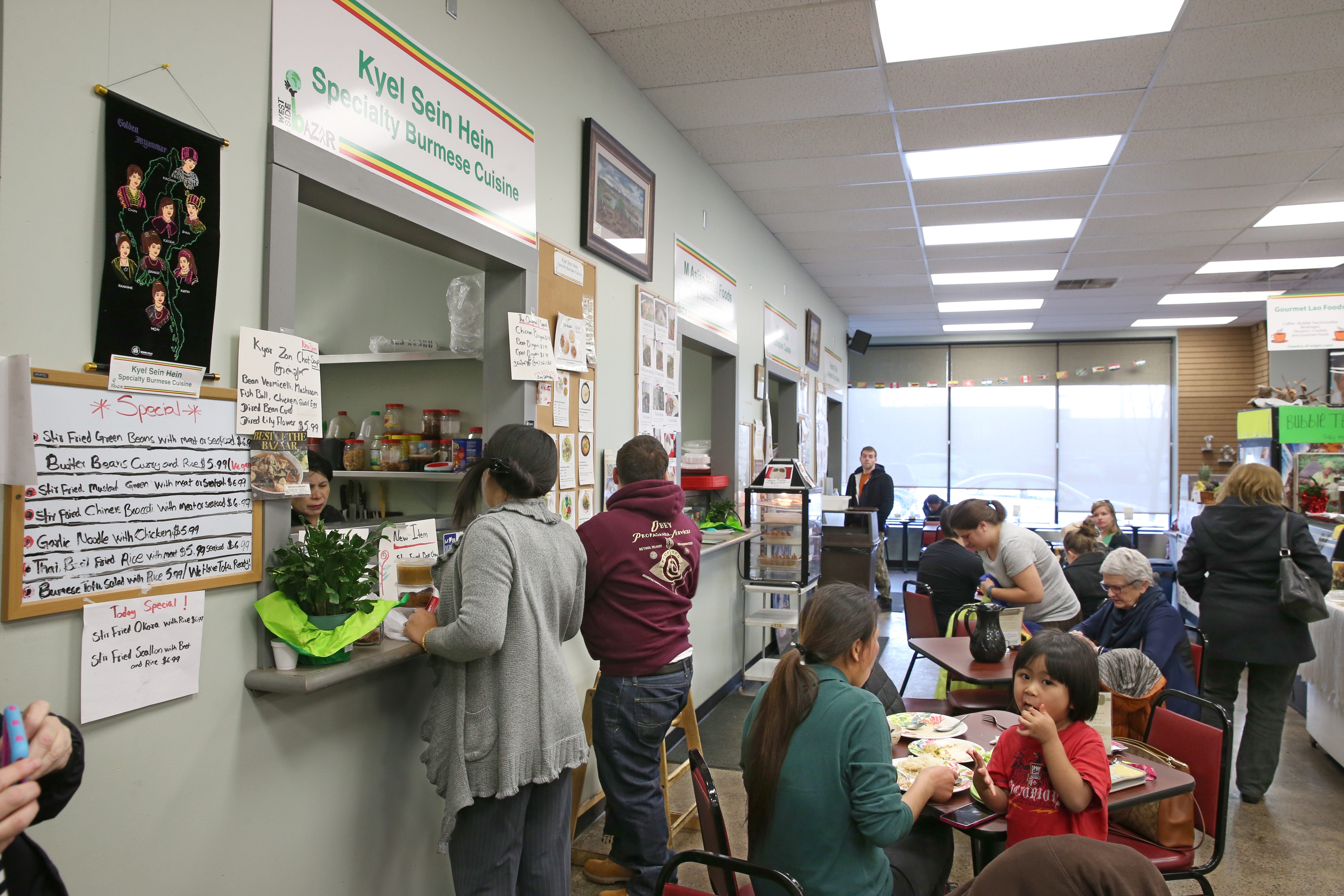 Customers place orders at the Kyel Sein Hein Burmese Cuisine window, at far left, at the West Side Bazaar.