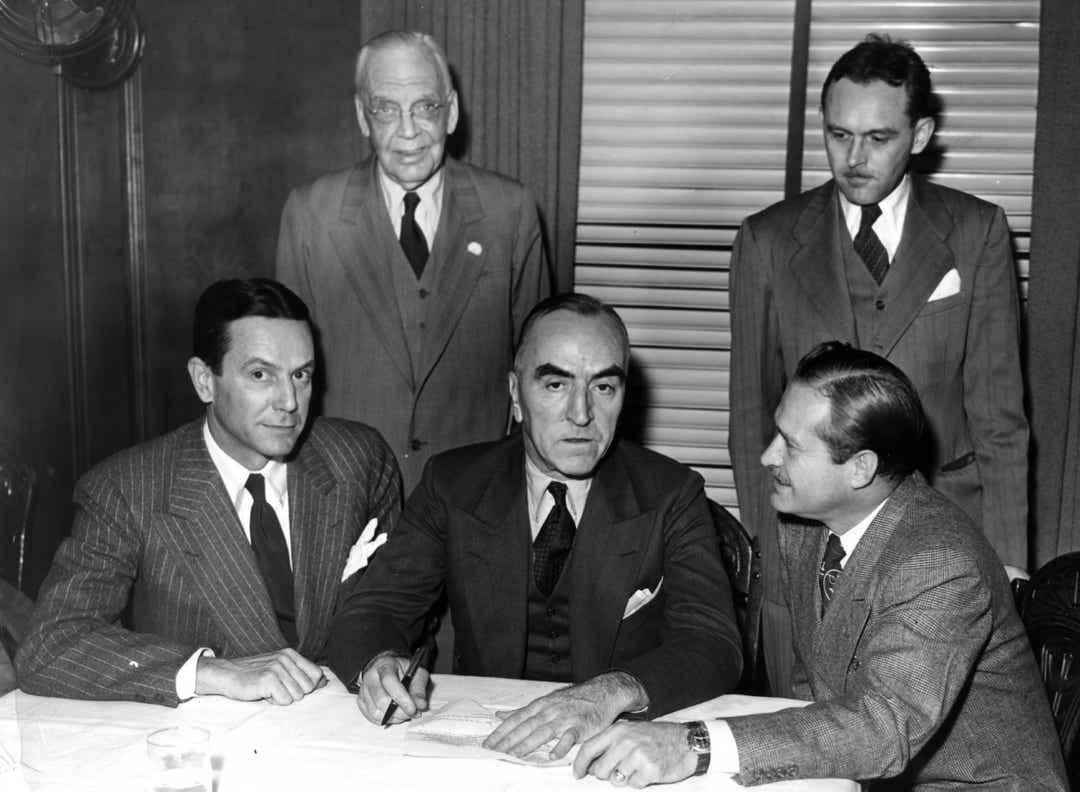 Seduti da sinistra, Tony Hulman, Eddie Rickenbacker e Wilbur Shaw siglano l'accordo che sancisce il passaggio dello Speedway all'imprenditore dell'Indiana. indystar.com