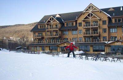A snowboarder glides in front of the Jay Peak Tram Haus Lodge in 2012.