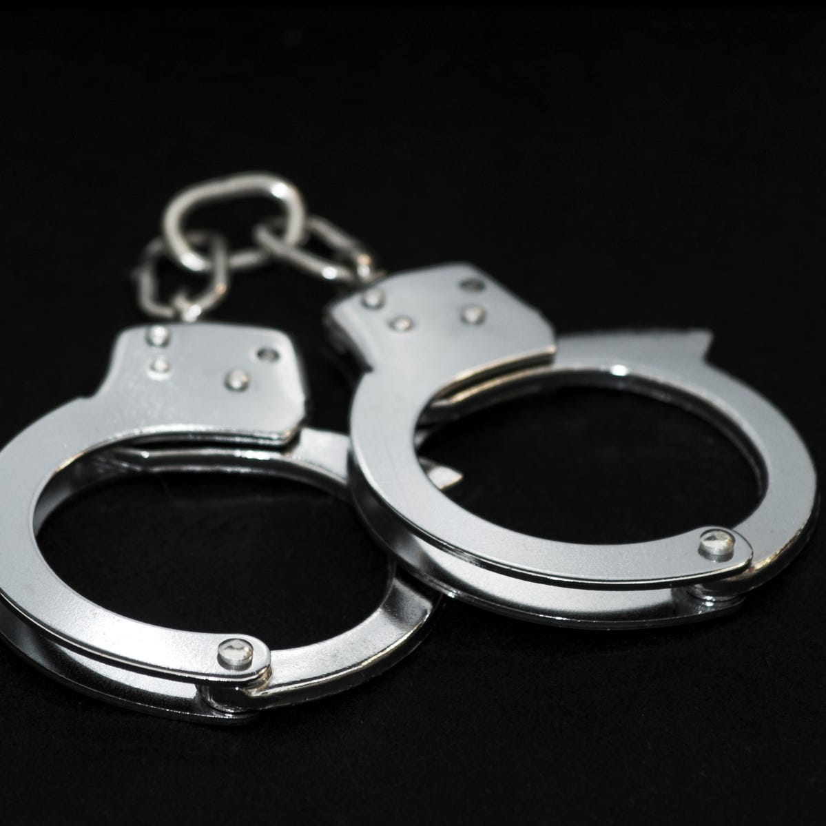 Steel handcuffs on a black background. Image has a DOF and focus is on front.