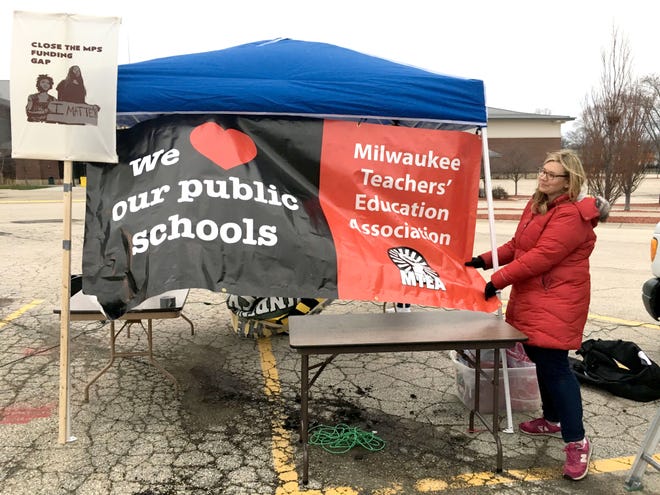 Melissa Zombor, communication director with MTEA (Millwaukee Teachers Education Association) hangs up a sign as advocates of neighborhood public schools gather to speak out on Gov. Scott Walker's proposed budget at a hearing at the State Fair Park Exposition Center in West Allis on Wednesday.